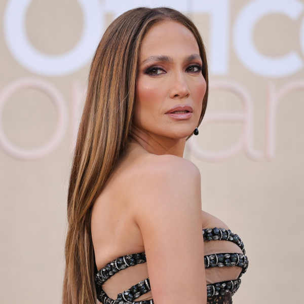 Jennifer Lopez poses on the red carpet for the premiere of the Office Romance with long straight hair and barelythere brows.